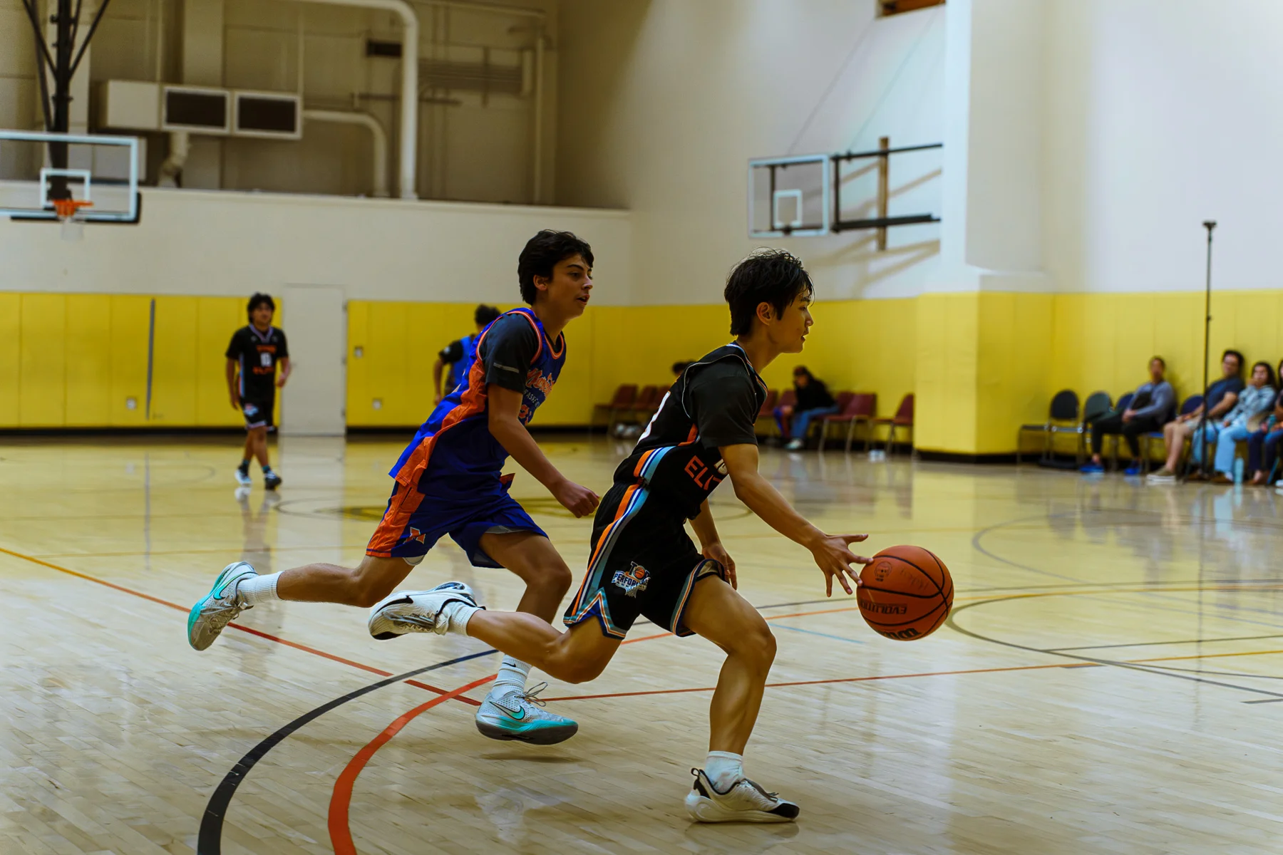 A TPB player drives past a defender during a basketball game
